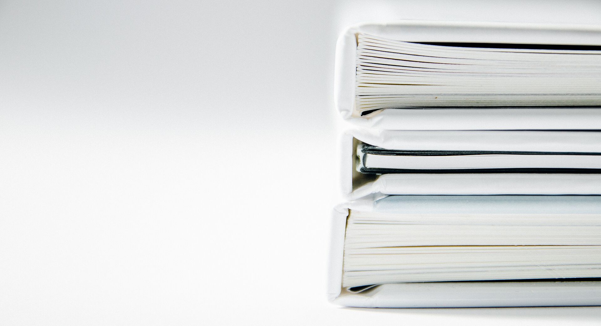 Gestapelte Hardcover-Bücher in Seitenansicht vor hellem Hintergrund.